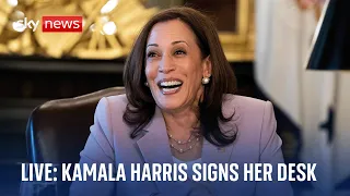 US Vice President Kamala Harris signs her desk in the ceremonial White House office